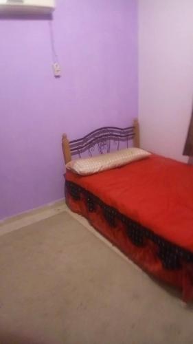 um quarto com uma cama com uma colcha vermelha em Haram City em Cidade 6 de Outubro