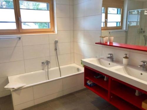 a bathroom with a tub and a sink and a mirror at Aiolos Apartments 6 Personen in Zermatt