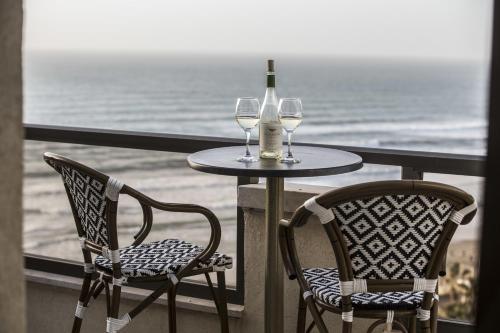 a table and two chairs with wine glasses on a balcony at Penthouse Apartment On The Beach in Bat Yam