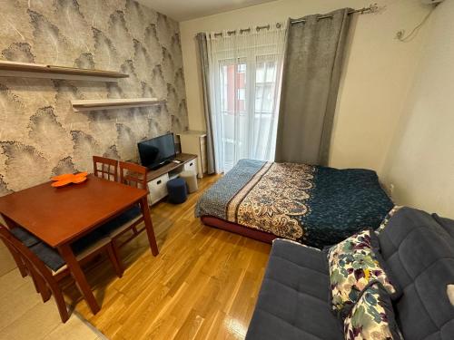 a bedroom with a bed and a table and a couch at Ania apartment in Podgorica