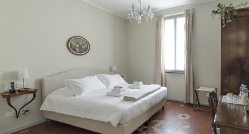 a bedroom with a bed with white sheets and a chandelier at Locanda San Bernardo in Vigevano