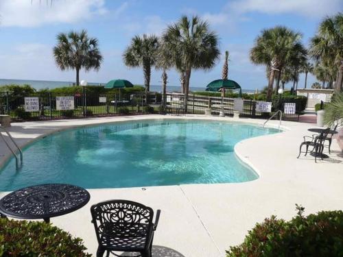 una piscina con sillas, mesas y palmeras en Ocean Front 53 Steps en Myrtle Beach