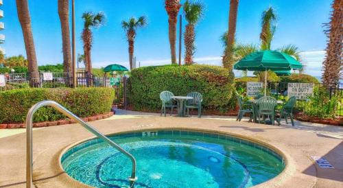 una pequeña piscina con sillas, mesas y palmeras en Ocean Front 53 Steps, en Myrtle Beach