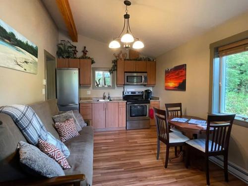 a living room with a couch and a table with chairs at Cozy Corner Cottage in Port Renfrew