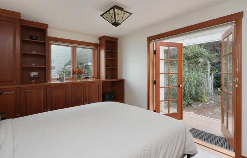 1 dormitorio con 1 cama y puerta corredera de cristal en WhidbeyBeachHouse, an Oceanfront Getaway on a Private Beach, en Langley