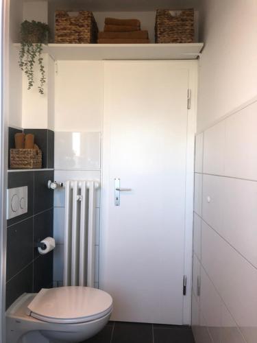 La salle de bains est pourvue de toilettes et d'une armoire blanche. dans l'établissement FeWo Ruhrnatur „Modern trifft Gemütlichkeit“, à Mülheim