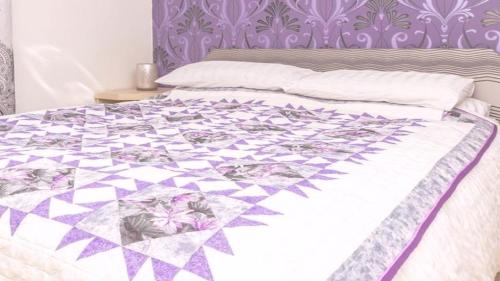 a bed with a purple and white quilt on it at Gialos Villa Mykonos Lux in Platis Gialos