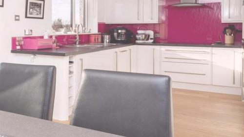 una cocina con armarios de color rosa y blanco, mesa y sillas en Gialos Villa Mykonos Lux en Platis Yialos Mykonos
