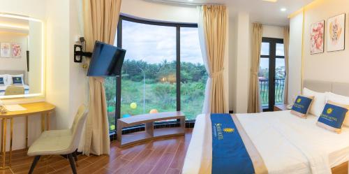 Schlafzimmer mit einem Bett, einem TV und einem Fenster in der Unterkunft SUNRISE Hotel Bạc Liêu in Bạc Liêu