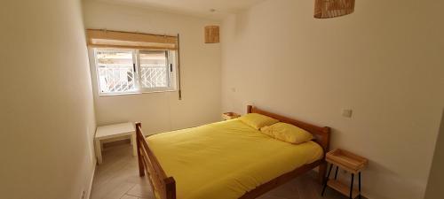 um pequeno quarto com uma cama amarela e uma janela em Coconut Monte Gordo em Monte Gordo