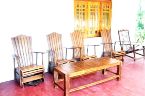 a group of chairs and a wooden table in a room at Impress Holiday Home in Anuradhapura