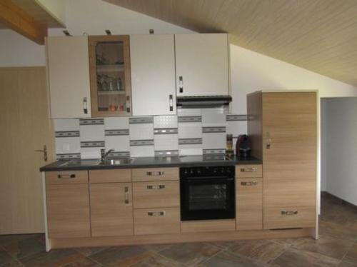 a kitchen with wooden cabinets and a stove top oven at schöner Aufenthalt in Le Noirmont