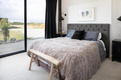 a bedroom with a large bed and a large window at NOMAC No8, Luxury holiday home, Twizel in Twizel