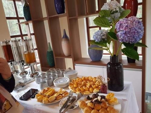 une table avec des assiettes de pâtisseries et un vase avec des fleurs dans l'établissement Omirita Resort Dalat, à Đà Lạt