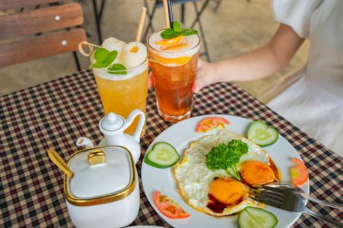 une table avec une assiette de nourriture et deux boissons dans l'établissement Omirita Resort Dalat, à Đà Lạt