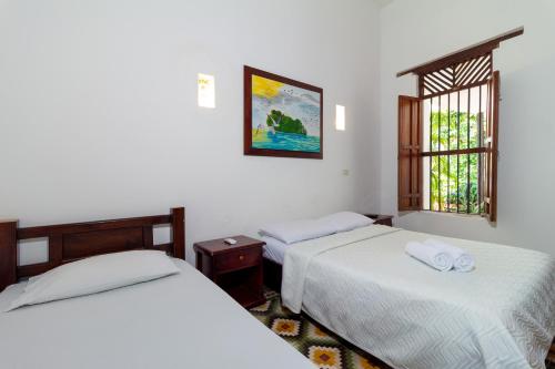 1 dormitorio con 2 camas y ventana en Casa Pedro Romero, en Cartagena de Indias
