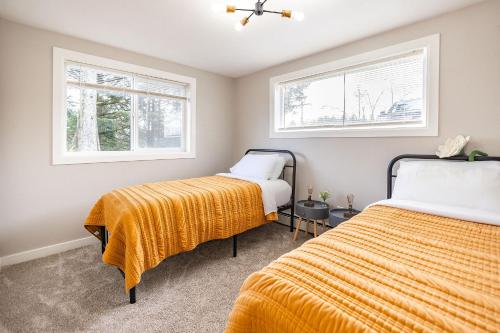 two beds in a room with two windows at THE SHORELINE- Beach Access, Ocean Views, Private in Kodiak