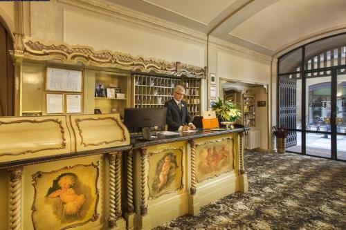 un hombre de pie en un escritorio en una biblioteca en Hotel Posta, en Reggio Emilia