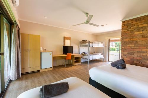 a room with two beds and a desk with a television at Contour Hotel Katherine in Katherine