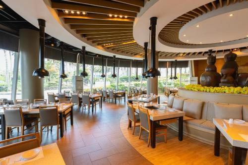 uma sala de jantar com mesas, cadeiras e janelas em Sono Belle Jeju em Jeju