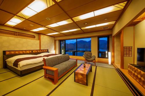 a bedroom with a bed and a couch and a tv at Kawaguchiya Kinosaki Riverside Hotel in Toyooka