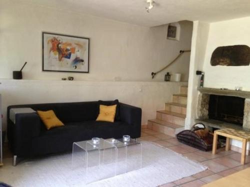 un soggiorno con divano nero e camino di Ursprüngliches, stilvolles Rustico a Malvaglia