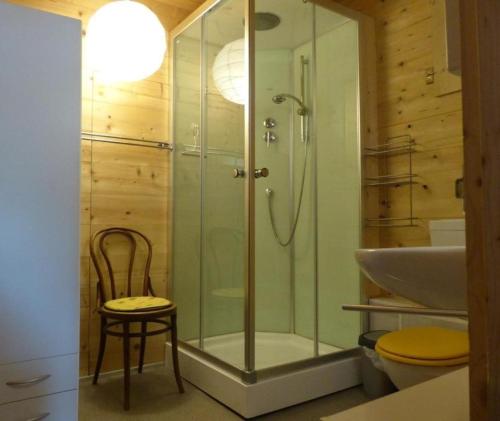 a bathroom with a shower and a chair and a sink at Alpenblick nord-ost in Frutigen