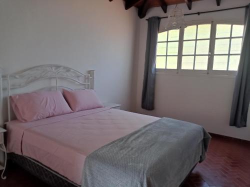 a bedroom with a bed with pink pillows and a window at Casa de la Amistad in Areguá