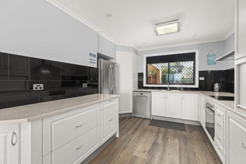 a kitchen with white cabinets and a window at Sea Eagle by Experience Jervis Bay in St Georges Basin