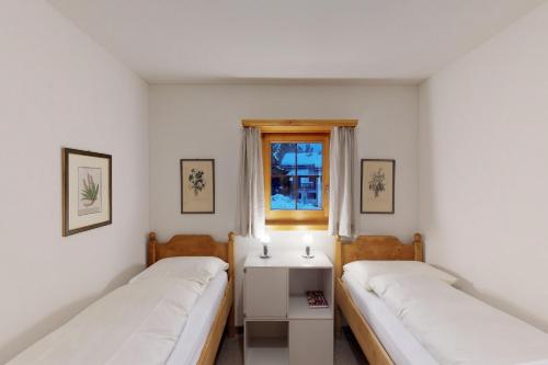 two beds in a room with a window at Apartment Pradè in Samedan