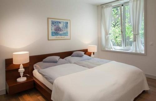 een slaapkamer met 2 bedden en een raam bij Tertianum Parkresidenz - moderne 25 Zimmer Wohnung direkt am Zürichsee in Meilen