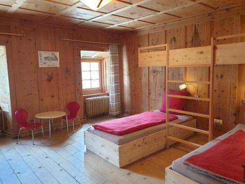 a bedroom with two bunk beds and a table at Barba Peder - BioBergün in Bergün