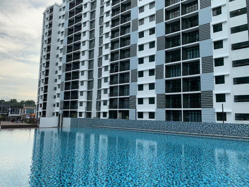 a swimming pool in front of two tall buildings at Desaru Utama Apartment with Swimming Pool View, Karaoke, FREE WIFI, Netflix, near to Car Park in Desaru