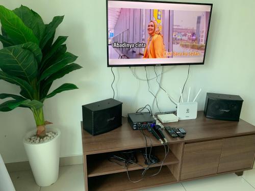 a flat screen tv sitting on top of a wooden entertainment center at Desaru Utama Apartment with Swimming Pool View, Karaoke, FREE WIFI, Netflix, near to Car Park in Desaru