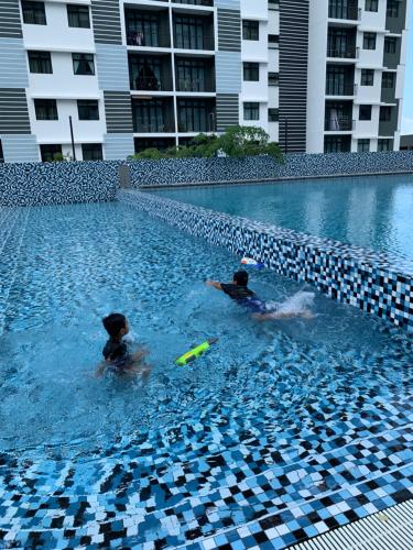 two people in a swimming pool with a frisbee at Desaru Utama Apartment with Swimming Pool View, Karaoke, FREE WIFI, Netflix, near to Car Park in Desaru