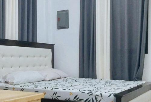 1 dormitorio con 1 cama con cortinas azules en RedDoorz Plus @ Remarkable Hotel Alcala Pangasinan 
