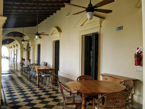 una sala da pranzo con tavoli, sedie e ventilatore a soffitto di Finca El Recreo a Cafayate