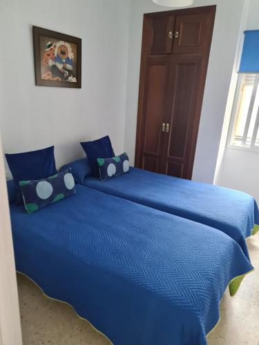 een blauw bed met blauwe lakens en kussens in een slaapkamer bij apartamento céntrico jerez calle tucan n17 in Jerez de la Frontera