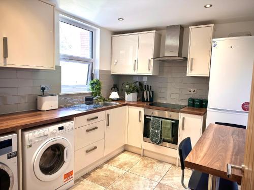 a kitchen with white cabinets and a washer and dryer at Room with private bathroom/Tv in Purley