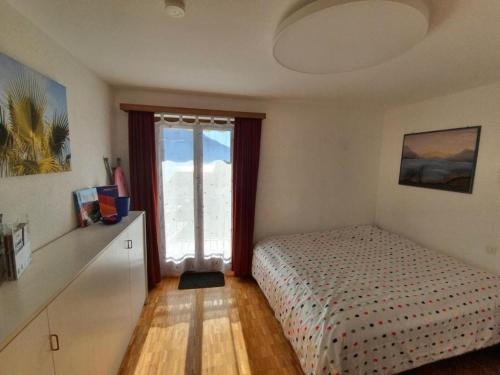 Schlafzimmer mit einem Bett und einem Fenster in der Unterkunft Casa Ghiggi - Zweizimmerwohnung "Ticino" in Brissago