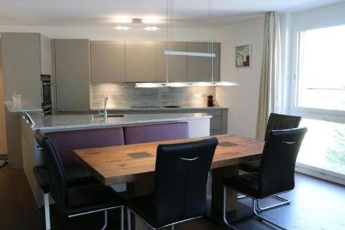 eine Küche mit einem Holztisch und schwarzen Stühlen in der Unterkunft Chavallera Casa Torri in St. Moritz