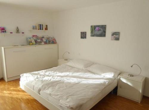 1 dormitorio con cama blanca y pared blanca en Casa Ghiggi - Dreieinhalbzimmerwohnung "Asia", en Brissago