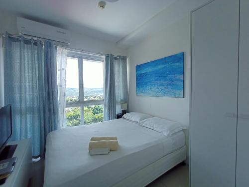 een witte slaapkamer met een groot bed en een raam bij Prima at Primavera Residences in Cagayan de Oro