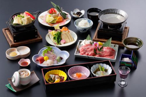 una mesa con muchos platos de comida. en Midagahara Hotel, en Tateyama