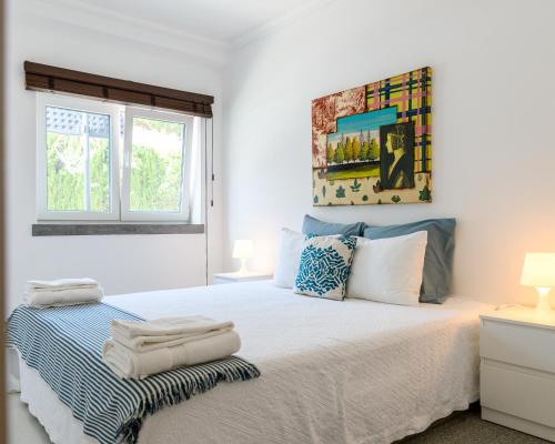 ein weißes Schlafzimmer mit einem Bett mit Handtüchern darauf in der Unterkunft VILLA MONZA CASCAIS in Cascais