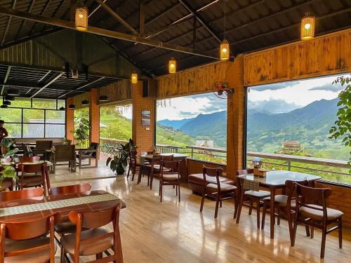 un restaurante con mesas y sillas y vistas a las montañas en Catcat Garden House, en Sa Pa