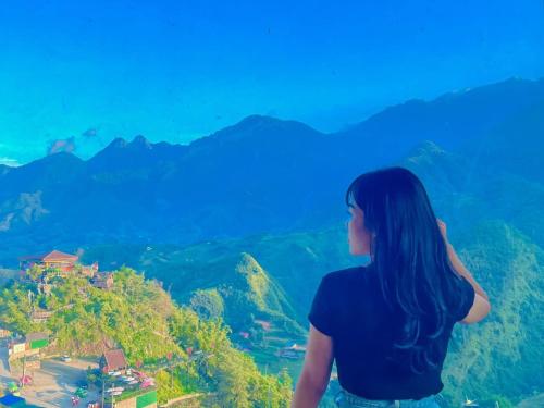 a woman standing on top of a mountain looking at a city at Catcat Garden House in Sa Pa