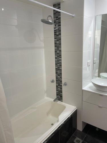 a white bathroom with a tub and a sink at Dee Why Beach - Studio 29 Surfrider in Deewhy