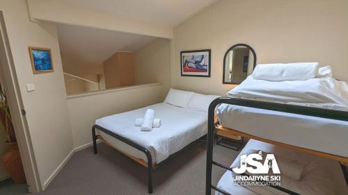 a small room with two beds and a mirror at Razorback 2 in Jindabyne