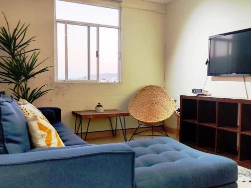 a living room with a blue couch and a tv at Moderno y Tradicional, elegante departamento en Oaxaca in Oaxaca City